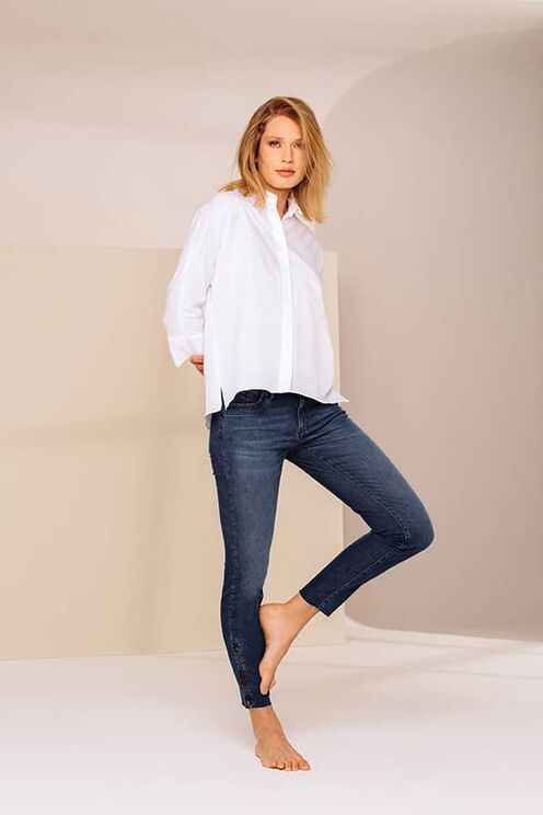 blondes Model trägt weiße Bluse und blaue Jeans der Modemarke Raffaello Rossi
